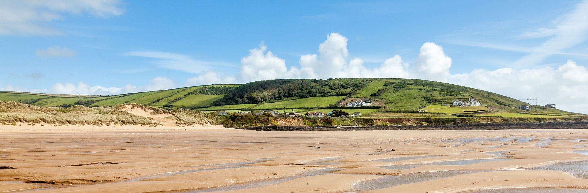A view over the sand at low tide looking towards the headland at Croyde Bay Beach in Devon
