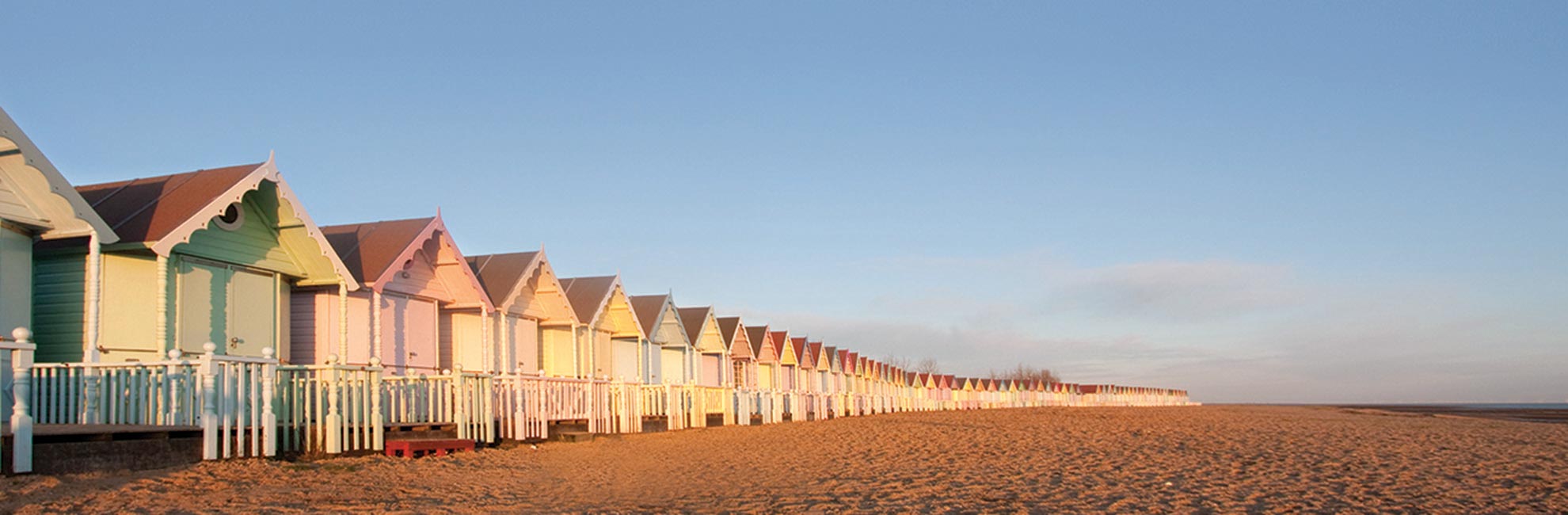 Colourful beach huts at sunrise on an Essex beach