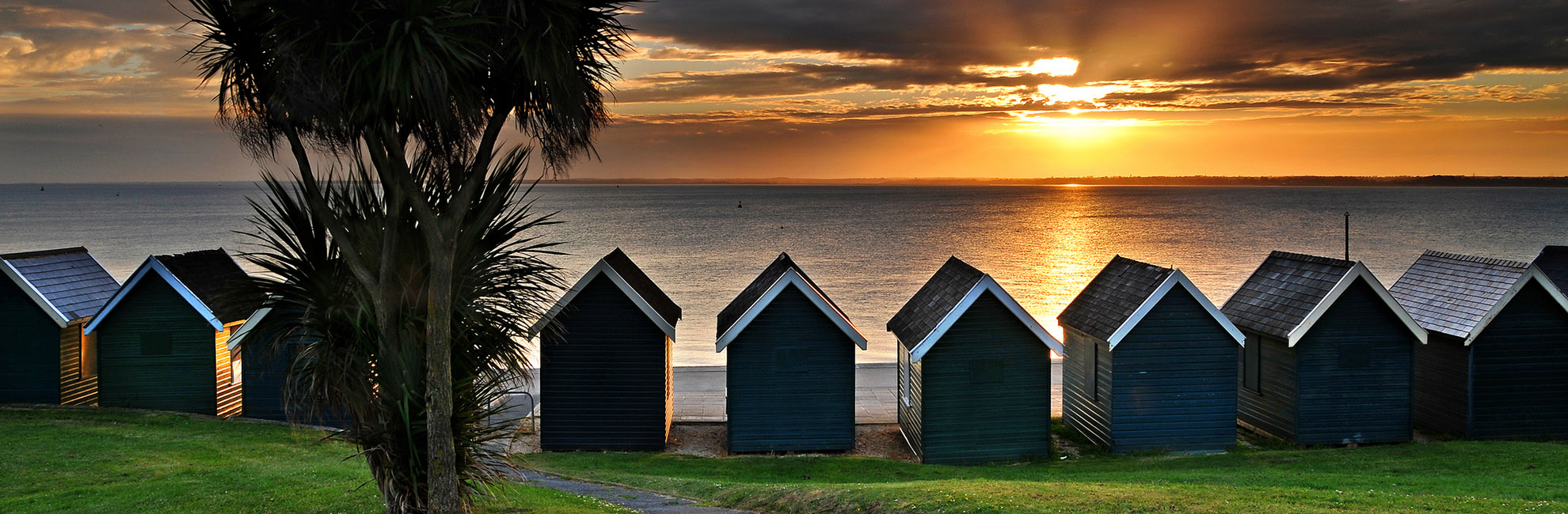 Beach huts overlooking a sunset over the sea
