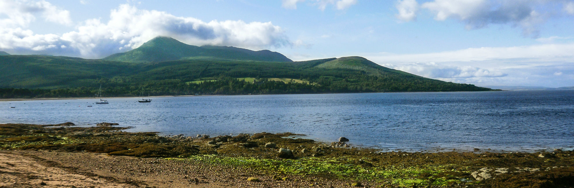 A peaceful bay surrounded by green mountains and hillside on the Isle of Arran in Scotland