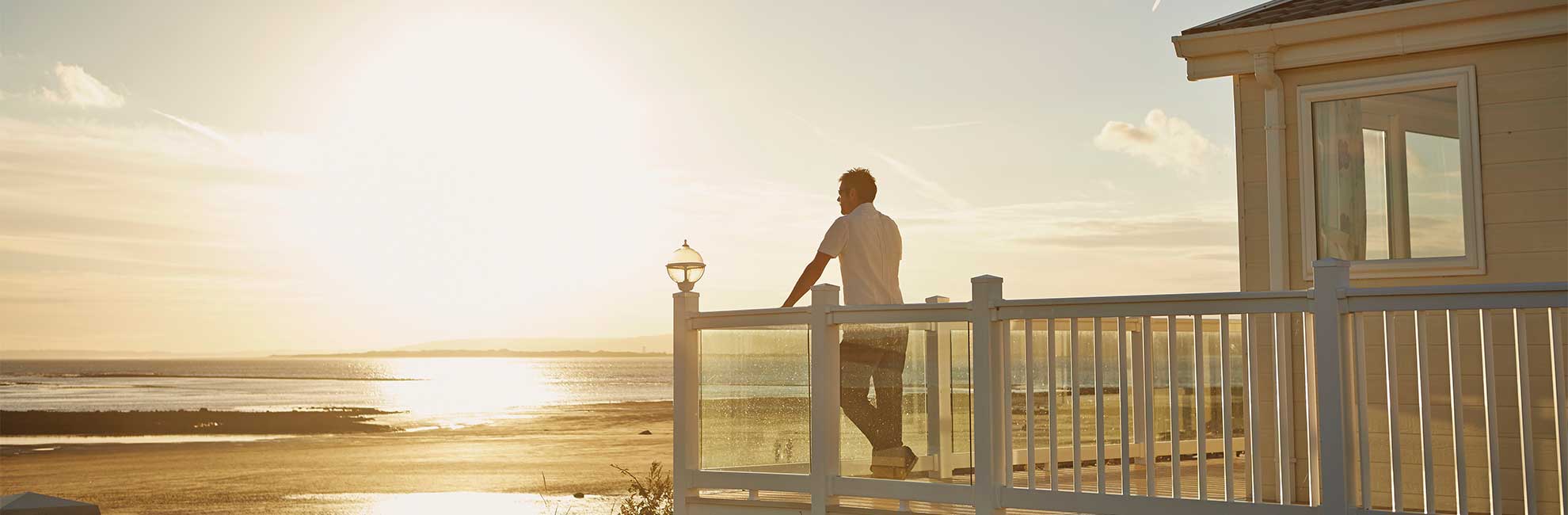 A man enjoying the sunset over the sea from his lodge veranda
