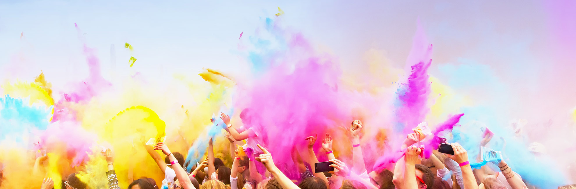 A crowd throwing paint in the air at a festival