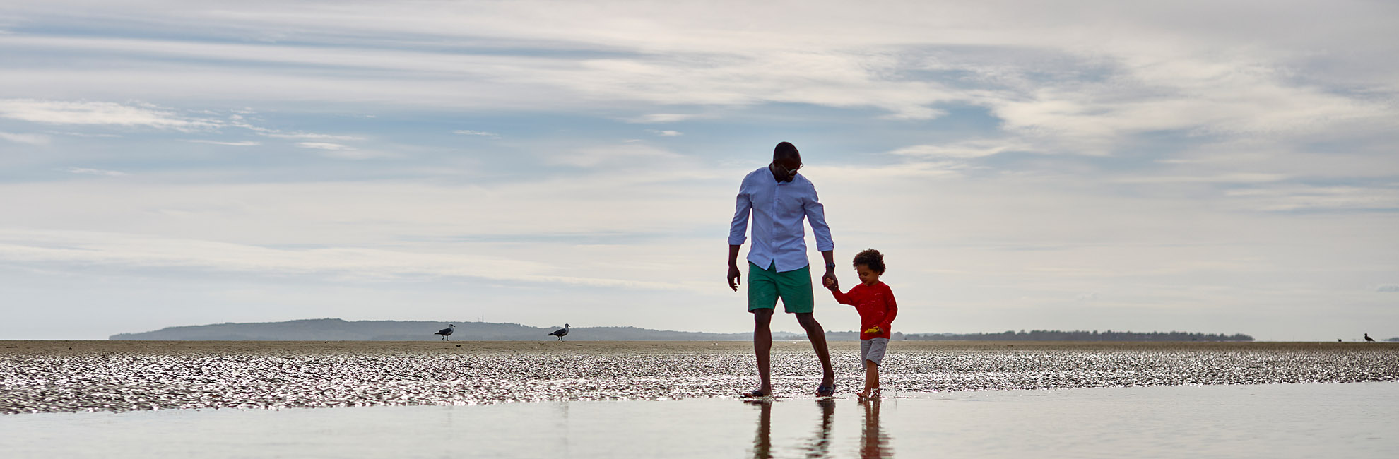 A father and son walking along Camber Sands Beach