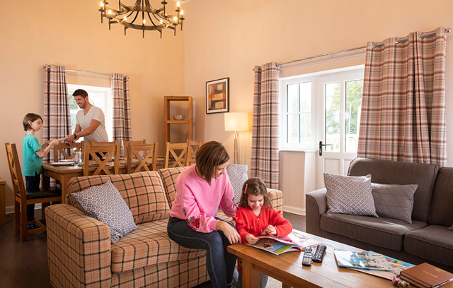A family relaxing in the living and dining area of their cottage