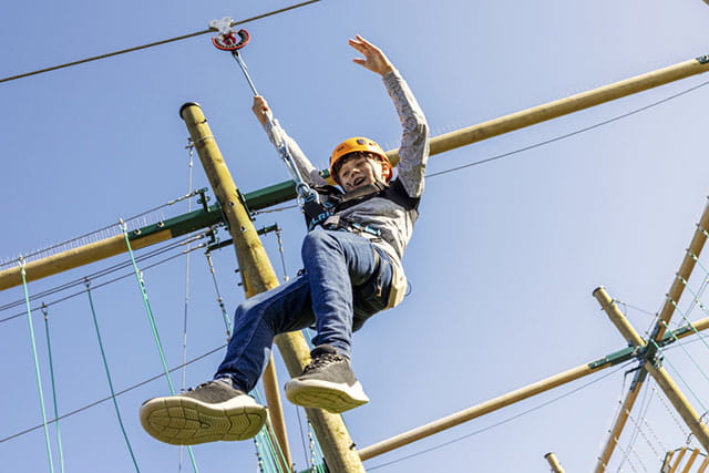A boy flying down the high ropes zip line at Parkdean Resorts