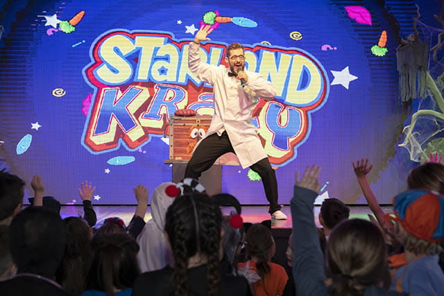 A performer on stage entertaining an audience of children at a show