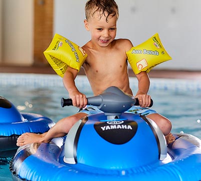A boy using an inflatable jet ski in the indoor swimming pool