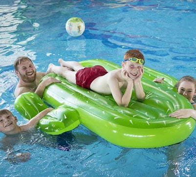 A family playing on an inflatable in the indoor swimming pool
