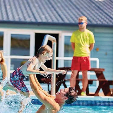 A lifeguard overseeing people in an outdoor swimming pool