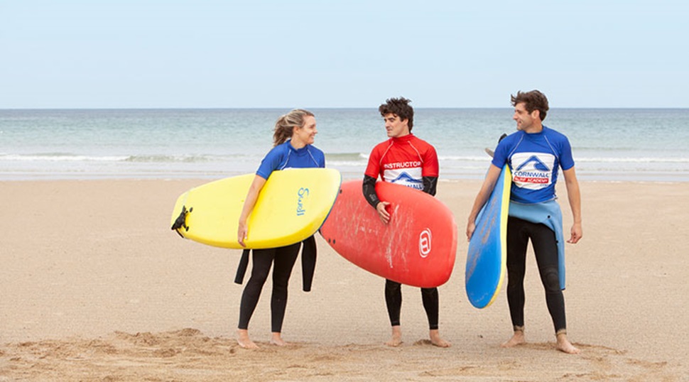 Three children walking on the beach holding surf boards