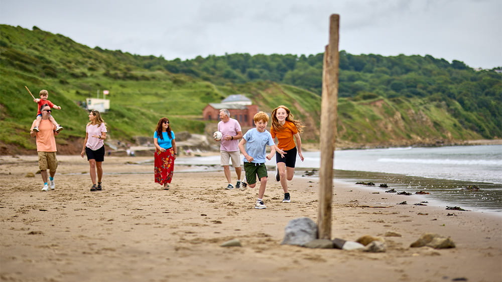 A family and grandparents walking along a UK beach