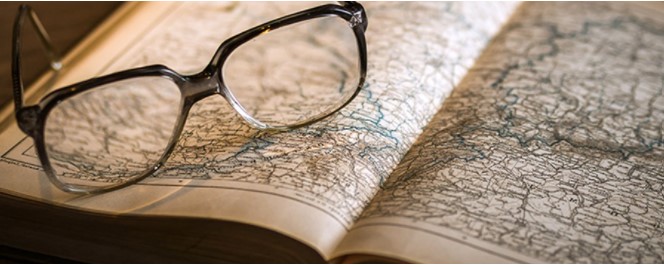 Reading glasses resting on a book of maps