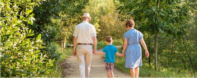 A boy walking along a country path with his grandparents