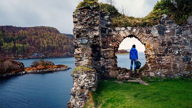 A person standing at a viewpoint overlooking a Loch in Scotland