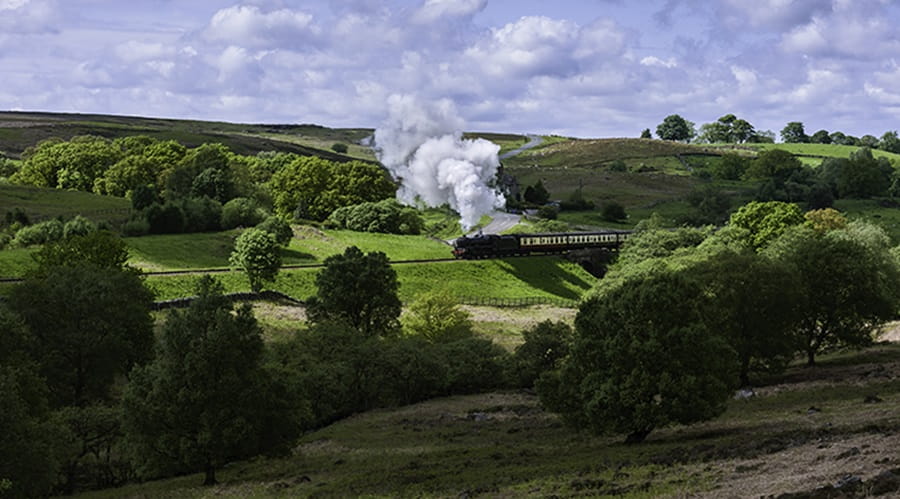 Train blowing steam in Yorkshire countryside