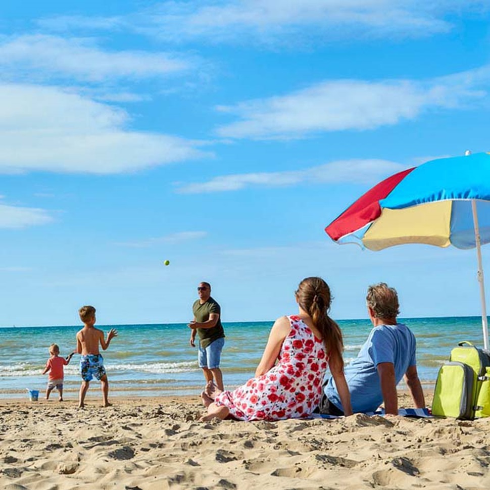 A family relaxing under an umbrella by the sea on Camber Sands Beach