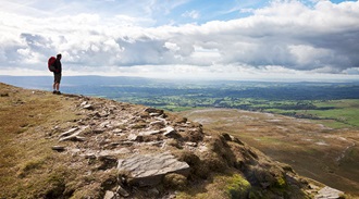 a man stood on a ridge looking over a breathtaking view of the Yorkshire dales