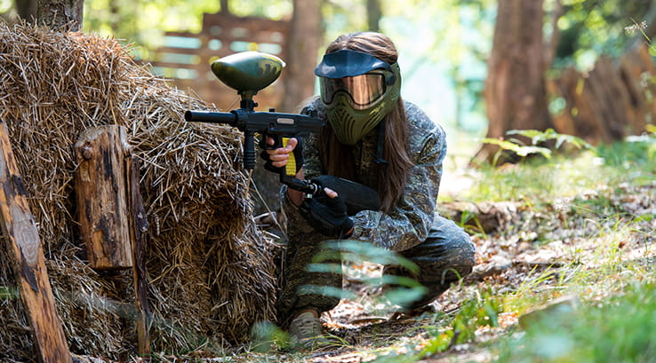 Survival paintball player hiding behind tree