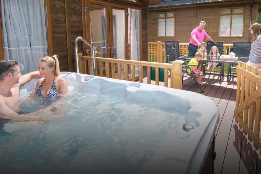 Couple sat in a hot tub on the veranda at Parkdean Resorts
