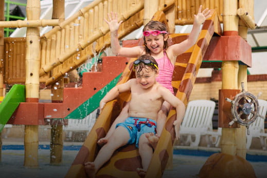 Brother and sister sliding down a waterslide at Parkdean Resorts