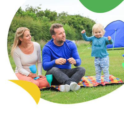Parents with a young child sat outside their tent on the touring and camping field at Breydon Water Holiday Park