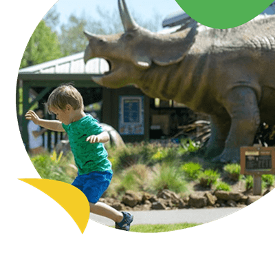 Little boy in front of large replica dinosaur