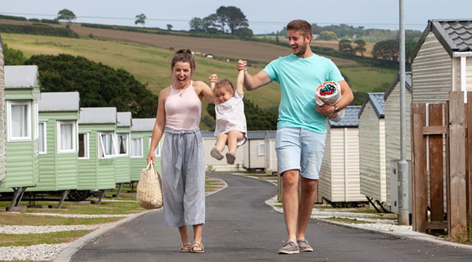 couple walking down path between caravans and holding hands with a toddler