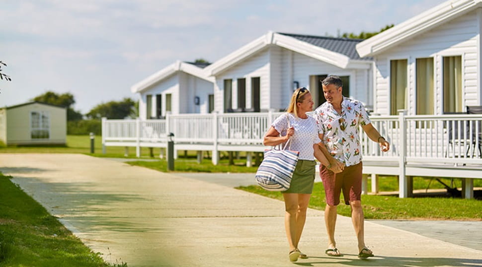 A couple strolling past the lodges on a sunny day at St. Margaret's Bay