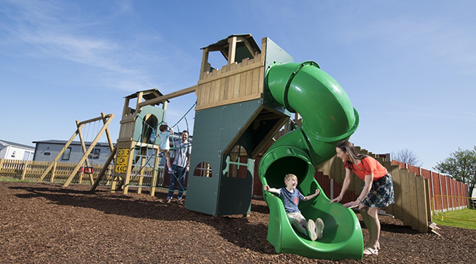 A child coming down the slide to his mother on the adventure playground
