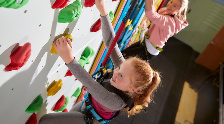 Two girls scaling the indoor climbing wall