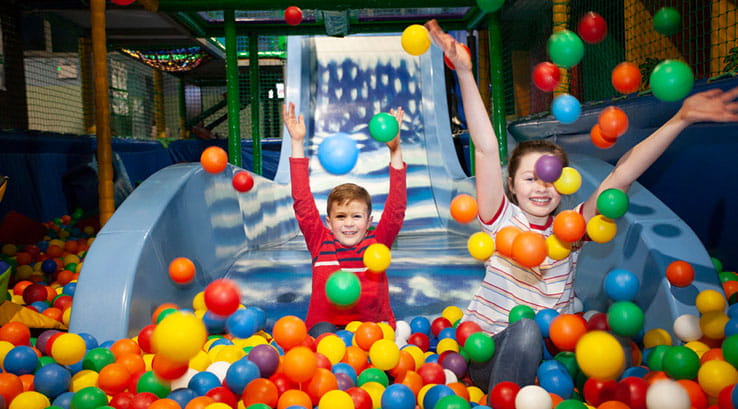 Kids sliding down the slide into the ball pool at the indoor soft play area