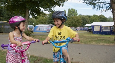 Two children riding bikes on the campsite