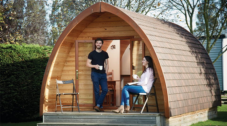 couple having a drink outside a wooden glamping pod